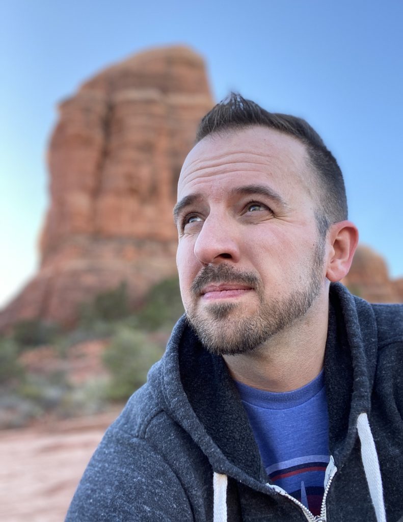 Headshot of Lincoln wearing a hoodie in 2020, somewhere in Arizona with a bluff in the background, looking into the distance like he's some kinda thought leader.